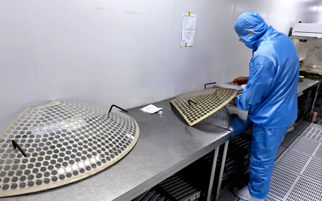 Technician preparing optical components for coating in a cleanroom