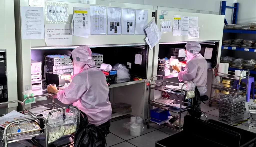 Technicians inspecting and handling optical components in a cleanroom