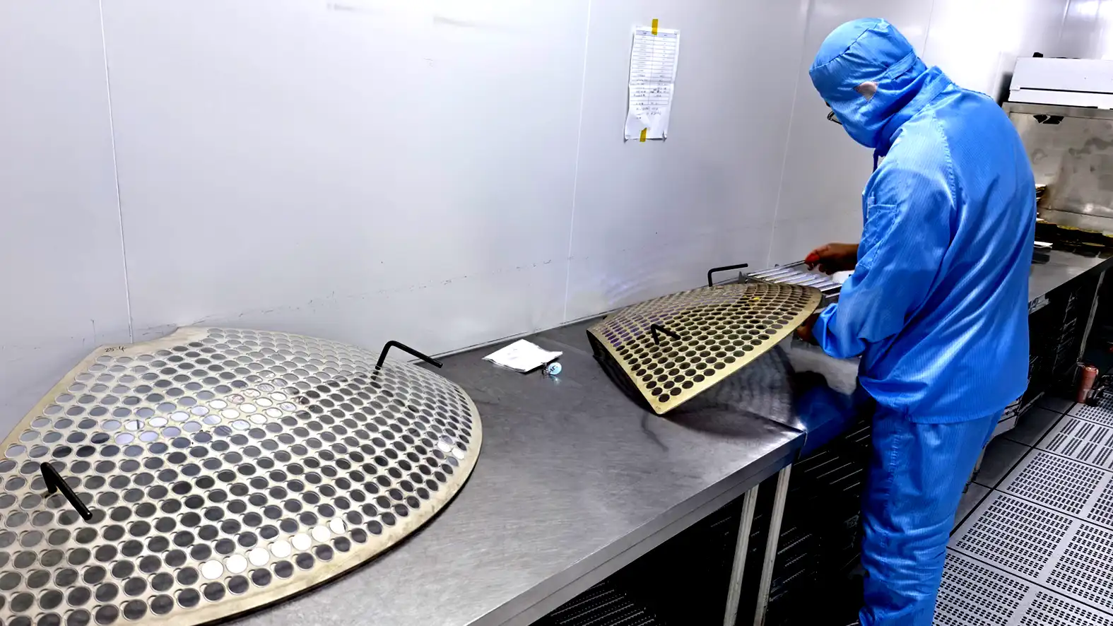 Cleanroom operator unloading coated optical components from coating fixtures after the coating process